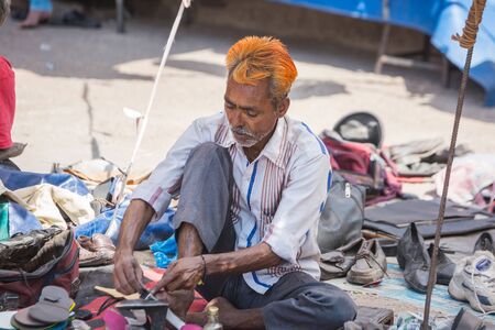 Jodhpur, India - March 07 2017: A man repairs shoes on the street, he is completely focused on his business.のeditorial素材