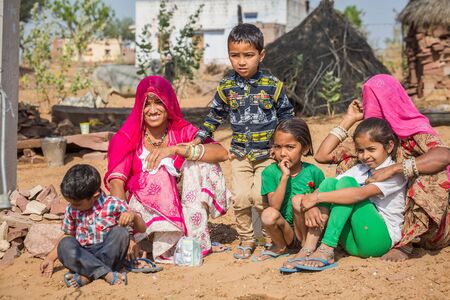 Jodhpur, India - March 08 2017: Two women and four children are sitting outside in the village. Women are smiling happily.のeditorial素材