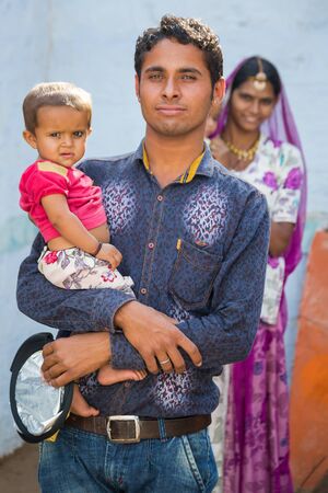 Jodhpur, India - March 08 2017: A young man smiles and holds his young child in his arms.のeditorial素材
