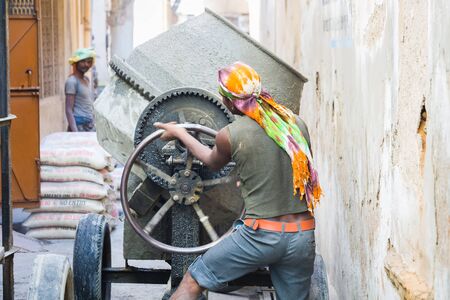 Udaipur, India - March 05 2017: A worker mixes concrete in a concrete mixer by hand.のeditorial素材