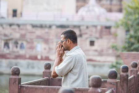 Jodhpur, India - March 08 2017: A man stands on the shore of the lake with his hands folded in a gesture of prayer. All his attention is in prayer.のeditorial素材