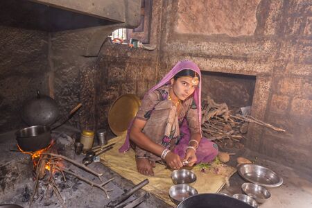Jodhpur, India - March 08 2017: A woman is cutting vegetables for cooking in the kitchen in the village.のeditorial素材
