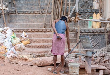 Udaipur, India - March 05 2017: Local man in the morning at the street takes water to the bucket.のeditorial素材