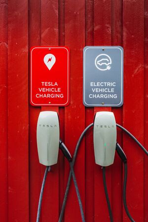 Tesla electric chargers on traditional red wooden house, rorbuer in the small fishing village of Nusfjord, Lofoten islands, Norway. Nusfjord, Norway - August 26 2019.のeditorial素材