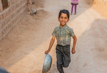 Jodhpur, India - March 08 2017: Young boy runs after car in the village.