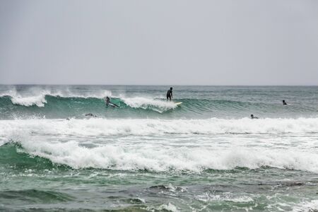 Arctic surfers surfing in Norwegian sea. Unstad, Norwegian village on Lofoten islands. Norwegian sea coastline. Winter water activities sport. Uttakleiv, Norway - August 26 2019.のeditorial素材