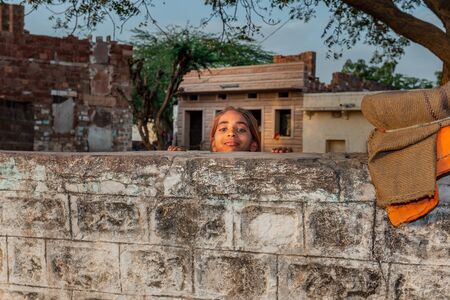 Jodhpur, India - March 08 2017: Cheerful girl watching over fence.のeditorial素材
