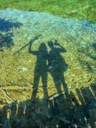 Shadows of tourists near waterfalls of one of the most astonishing places in the world at  Plitvice...