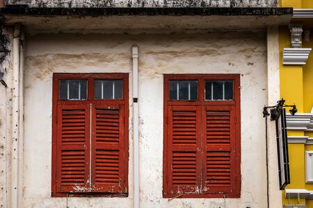 Wooden shutters on the windows in different shapes. Colorful buildings in old Phuket town in Thailand. Sino Portuguese style.の写真素材