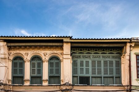 Wooden shutters on the windows in different shapes. Colorful buildings in old Phuket town in Thailand. Sino Portuguese style.の写真素材