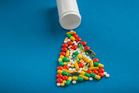 Opioid epidemic. Medication bottle and assorted pharmaceutical medicine pills, tablets and capsules over blue background.の写真素材