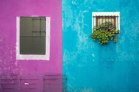 Blue and pink wall with windows with shutters at the famous island Burano, Venice, Italy.