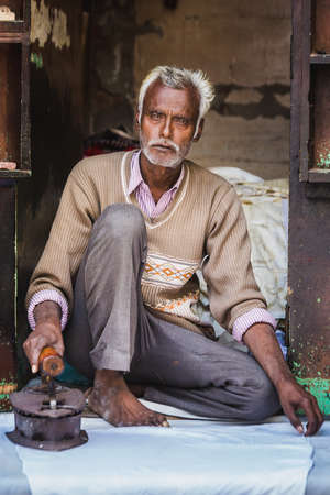 Vrindavan, India - March 12 2017: Indian man iron sheet with old iron at Vrindavan, India.のeditorial素材