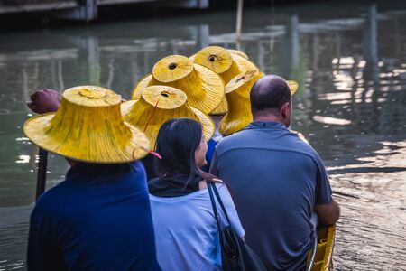 Yellow hats of tourists in a boat at famous Pattaya Floating Market which has traditional rowing boats. Villagers sell traditional foods and souvenirs.の写真素材