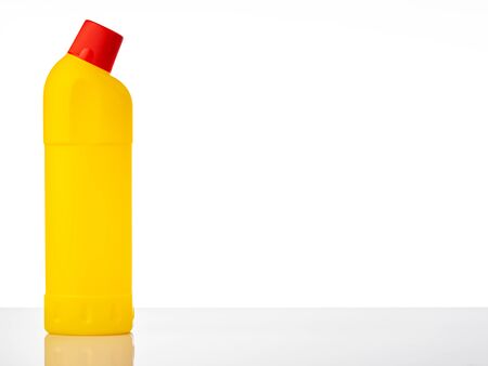 Yellow plastic bottle with detergent and cleaning supplies with reflection on the white background. Copy space.の写真素材