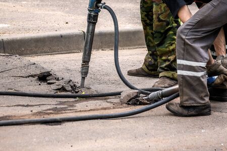 Professional workers in uniform repairing asphalt road with a jackhammer. Concept renovation, major...