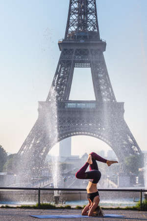 Woman in front of fountain and Eiffel tower in the background doing yoga. Paris, France - July 27 2018.のeditorial素材
