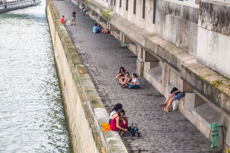 Tourists and Parisians in the evening enjoy the beauty of the Seine embankment, stroll, rest, drink and eat on the banks of the Seine in the center of Paris. Paris, France - July 27 2018.のeditorial素材