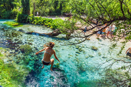 Girl jumps into blue eye is a karst spring, a rare geological object located in the south of Albania near the town of Saranda. Saranda, Albania - July 18 2018.のeditorial素材
