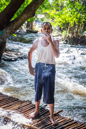 Local old man smoking a cigarette in white t-shirt at Rainforest of Doi Inthanon. Chiang Mai, Thailand - November 10 2017.のeditorial素材