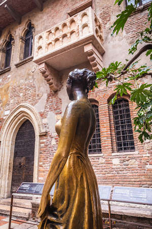 Statue and Patio and balcony of Romeo and Juliet house at golden sunset, Verona, Italy. Bronze statues of Juliet. Verona, Italy - February 05 2018.のeditorial素材