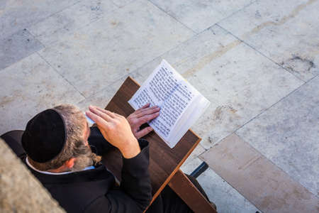 Jewish worshiper pray and reads from book written in hebrew near the Wailing Wall. Religious Jews celebrate the Sabbath near West Wall. Jerusalem, Israel. Jerusalem, Israel - April 19 2018のeditorial素材