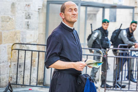 Priest looks up and police officers on duty near Damascus Gate at the old city of Jerusalem. They...