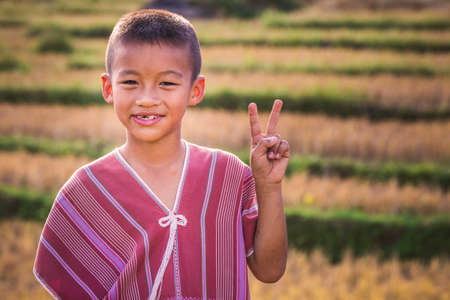 Local boy holding fingers in victory sign in the field at Doi Inthanon national park. Chiang Mai, Thailand - November 10 2017.のeditorial素材