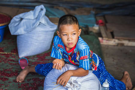 Local child play on the floor at famous long neck tribe village in Chiang Mai, Thailand. Chiang Mai, Thailand - November 12 2017.のeditorial素材