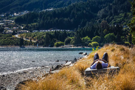Man sleeping on a rock with book on his face at Queenstown New Zealand, South Island. Queenstown, New Zealand - December 18 2017.のeditorial素材