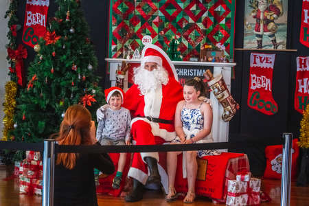 Santa Claus with two children near the tree in the lobby of shopping center. Dunedin, New Zealand - December 20 2017.のeditorial素材
