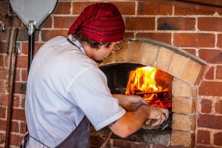 Cook makes pizza in the oven at Dunedin, New Zealand. Dunedin, New Zealand - December 20 2017.のeditorial素材
