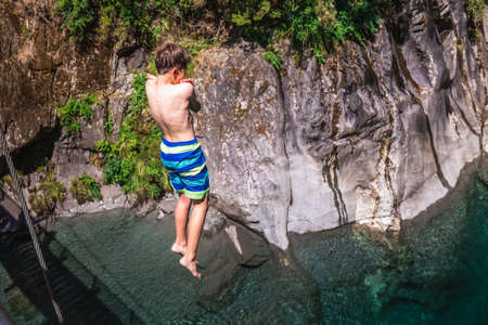People jump from the swing bridge on Blue Pool in Wanaka, New Zealand. Mount Aspiring, New Zealand - December 22 2017.のeditorial素材