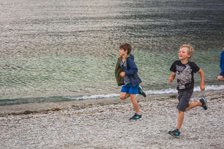 Young boys run at the beach of Queenstown New Zealand, South Island. Queenstown, New Zealand - December 17 2017.のeditorial素材
