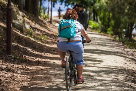 Obese woman on a bicycle at Queenstown New Zealand, South Island. Queenstown, New Zealand - December 18 2017.のeditorial素材