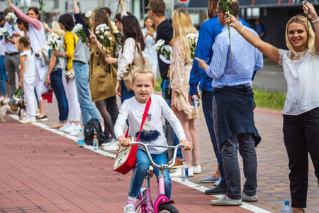 Child on a bicycle and people holding flowers during peaceful protests against stolen presidential elections in Minsk, Belarus. Minsk, Belarus - August 15 2020.のeditorial素材