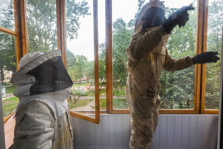 Workers in protective suits try to destroy bee hive on a balcony. It is a job for the professionals pest control. Minsk, Belarus - September 02 2020.のeditorial素材