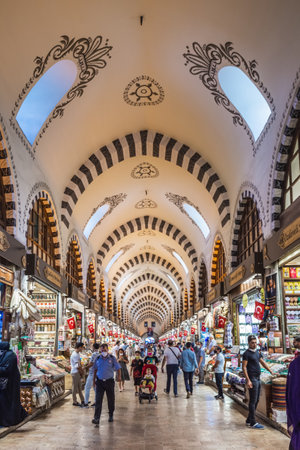 People shopping in the Grand Bazar, handmade pillows, bags and carpets are on the wall for sale. Souvenirs in famous Grand Bazaar. Istanbul, Turkey - September 30 2020.のeditorial素材