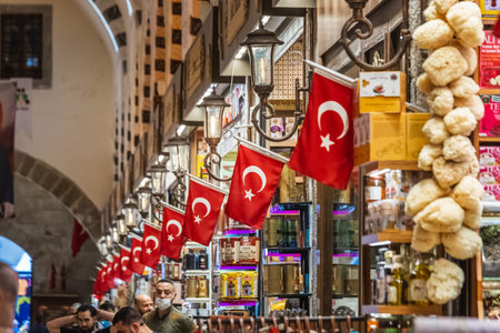 People shopping in the Grand Bazar, handmade pillows, bags and carpets are on the wall for sale. Souvenirs in famous Grand Bazaar. Istanbul, Turkey - September 30 2020.のeditorial素材