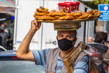 In Turkey the locals prefer hand-made bread, each family buying at least 5 breads each day. Simit seller at the street. Istanbul, Turkey - September 30 2020.のeditorial素材