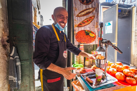 Local Turkish man makes a fresh pomegranate juice at his fruit stall. Pomegranate juice is a famous local beverage in Turkey. Istanbul, Turkey - September 30 2020.のeditorial素材