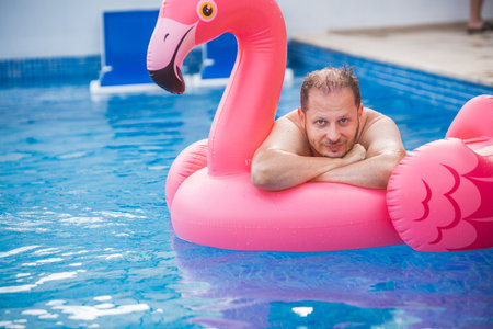 Cheerful man on flamingo rubber ring