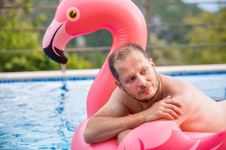 Cheerful man on flamingo rubber ringの写真素材