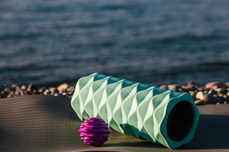 Rolled fitness ball and roll lie on the yoga mat by the sea. Sport outdoors concept.の写真素材