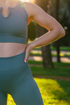 Sport and fitness outdoors close up of the unrecognisable sportive athletic young female fitness coach in sportswear doing physical stretch exercises in green summer park. Sport outdoors concept.の写真素材