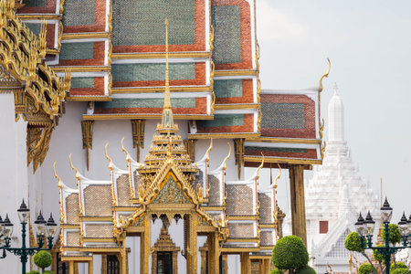 Ornately decorated and golden roof of the Royal Hall of Dusit Maha Prasat against the sky on a sunny...