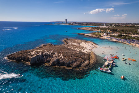 A stunning aerial view of a tropical coastline featuring clear turquoise waters, sandy beaches, anchored boats, and a scenic rocky island.の写真素材