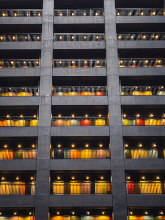 Geometric apartment building at night, featuring colorful doors and balconies, creating a vibrant...
