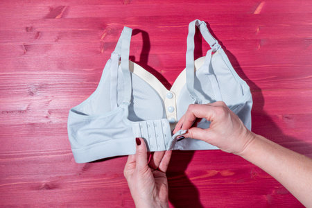 Female hands holding a bra on a red wooden background. top view.の写真素材