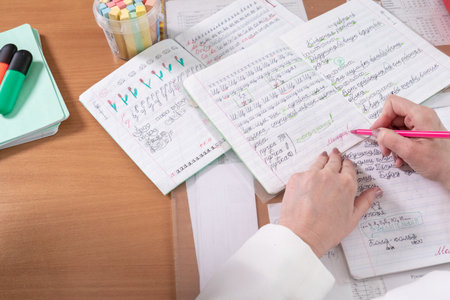 Female student writing in notebook at desk in classroom. education concept.